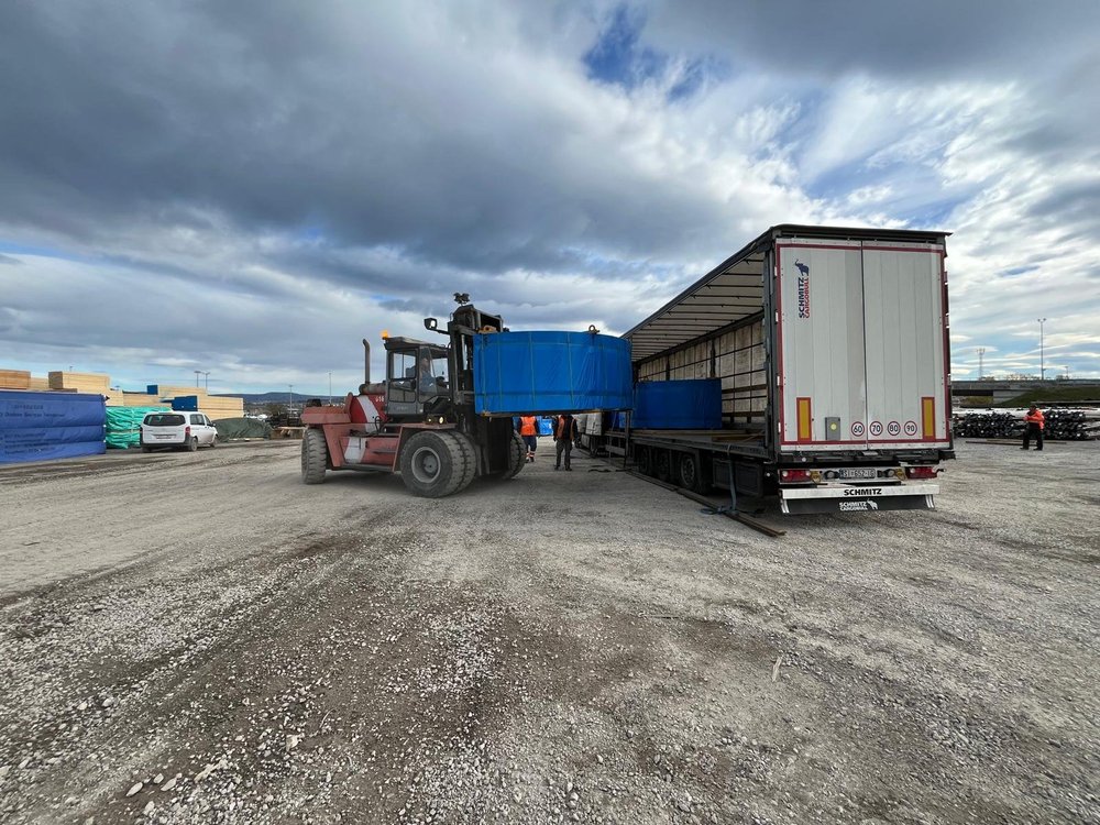 Warehouse interior with palletised goods and handling activity in progress.